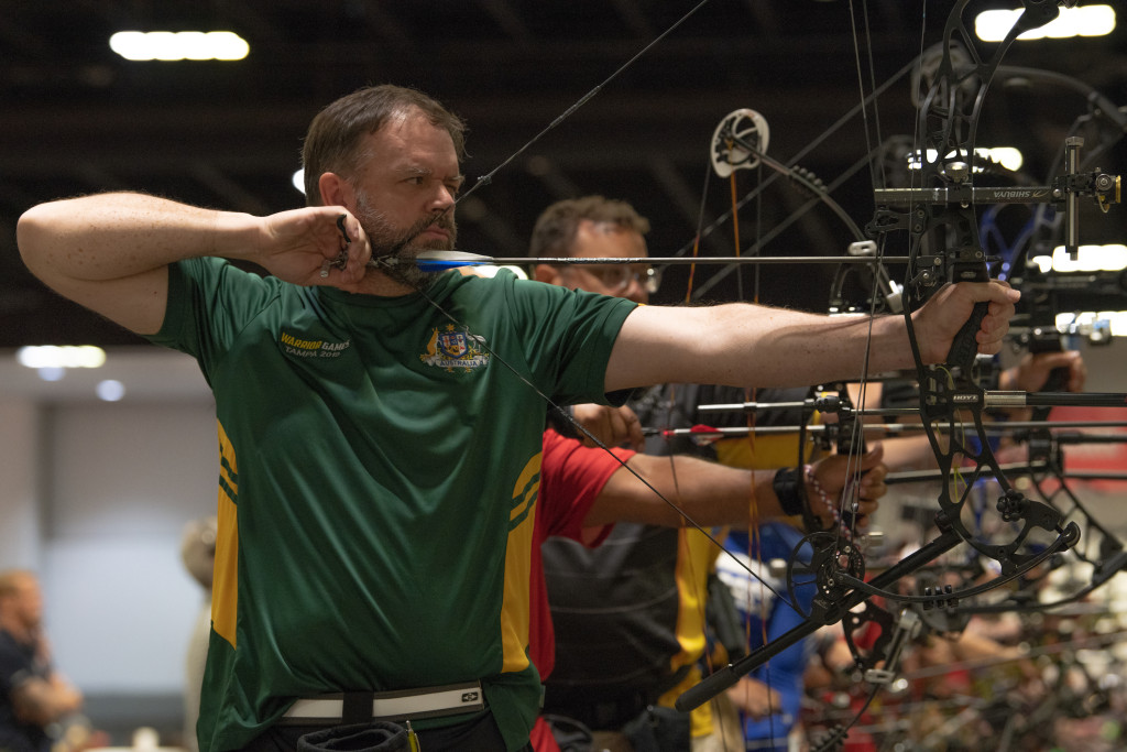 An athlete from team Australia draws an arrow during the archery preliminaries at the Tampa Convention Center during the 2019 DoD Warrior Games in Tampa, Florida, June 24, 2019. The DoD Warrior Games were established in 2010 as a way to enhance the recovery and rehabilitation of wounded, ill or injured service members and veterans and to expose them to adaptive sports. (U.S. Marine Corps Photo by Sgt. Bryce Hodges)